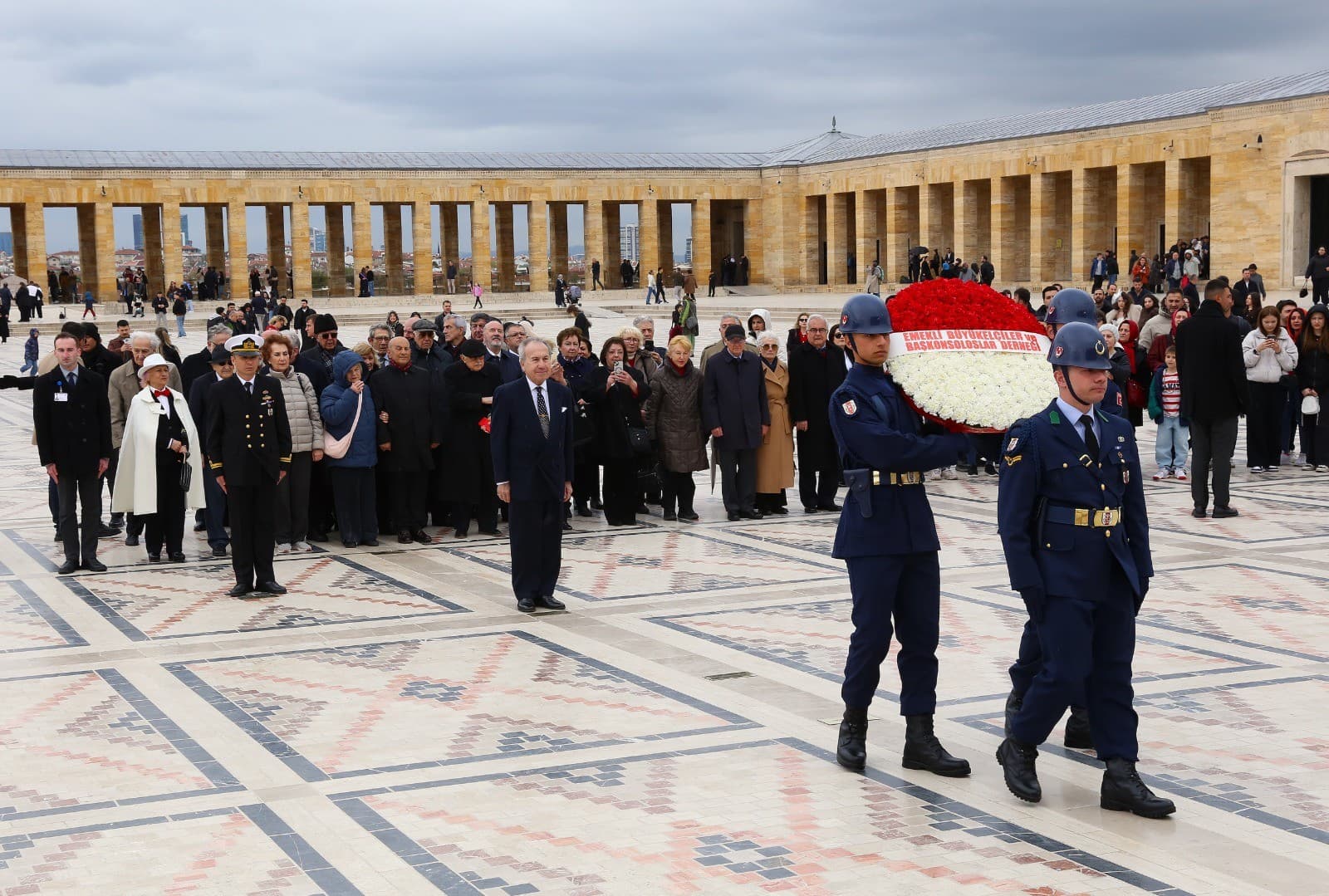 Anıtkabir'de askerî tören kıtası, Emekli Büyükelçiler ve Başkonsoloslar Derneği adına kırmızı-beyaz çelengi taşırken; arkada dernek üyeleri